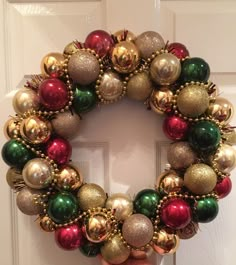 a hand holding a christmas ornament wreath in front of a door with ornaments on it