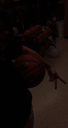 a person pointing at a basketball in the dark