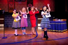 four women on stage with their hands in the air and one holding up her hand