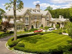 a large house with a car parked in front of it and landscaping around the driveway