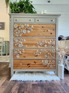 a dresser with flowers painted on the drawers and white fur rug in front of it