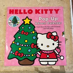 the hello kitty pop - up calendar is displayed in front of a pink background with snowflakes and a christmas tree