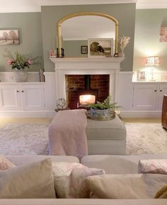 a living room filled with furniture and a fire place under a mirror on the wall