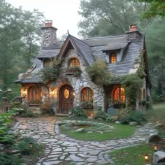 a stone house in the middle of a forest with lights on it's windows