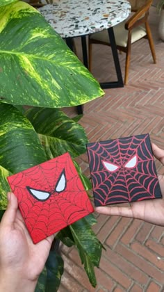 two spider - man coasters are being held by someone's hands on a brick patio