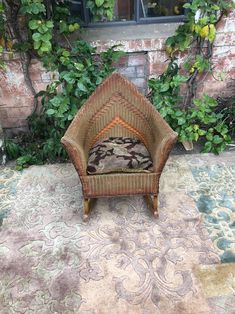 a wicker chair sitting in front of a brick wall with ivy growing around it