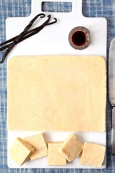 a cutting board topped with cut up cheese next to a knife and some other items