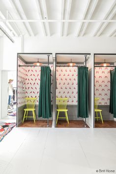 two green chairs are sitting in front of the wallpapered closets that have curtains on them