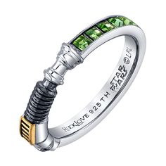 a ring with green stones in the middle and two tone gold accents on each side