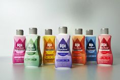 six bottles of different colored shampoos are lined up in a row on a table