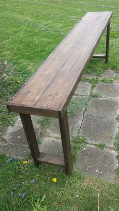 a wooden bench sitting on top of a lush green field next to a stone walkway