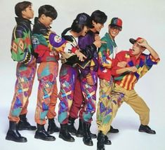 a group of young boys standing next to each other wearing colorful outfits and holding hats