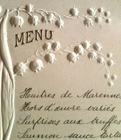 the menu is decorated with white flowers and leaves on it's side, along with handwritten writing