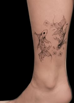 a woman's foot with two goldfish tattoos on it