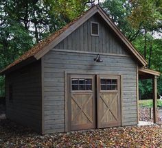 an outdoor storage shed with two doors on the front and one door open, surrounded by leaves