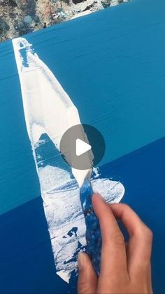 someone is painting the ocean with blue and white paint