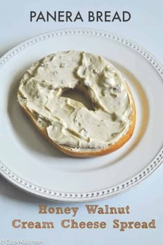 a white plate topped with a bagel covered in cream cheese spread on top of it