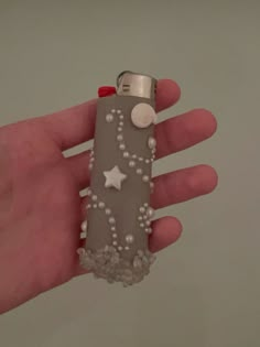 a hand holding a lighter with beads and stars on it