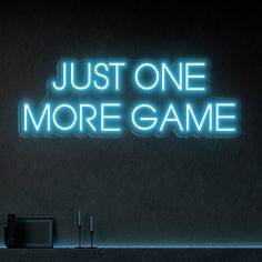 a neon sign that says just one more game next to two speakers and a tv