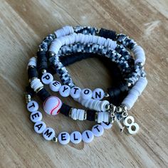 two bracelets with baseball charms on them sitting on top of a wooden table next to each other