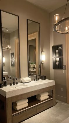 a bathroom with two sinks, mirrors and lights on the wall above them is shown