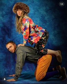 a man and woman posing for a photo in front of a blue background wearing colorful clothing