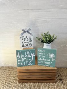 two small wooden signs sitting on top of a table next to a potted plant