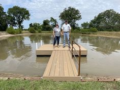 two people standing on a dock in the water