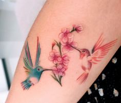 a woman's arm with two hummingbirds and flowers painted on the back of her arm