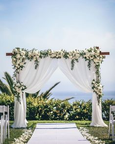 an outdoor wedding ceremony setup with white flowers and greenery on the aisle, overlooking the ocean