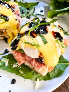 two pieces of meat and cheese on top of green leafy greens in a white plate