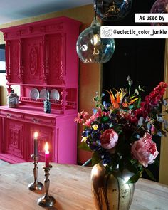 a vase filled with flowers sitting on top of a wooden table next to a candle