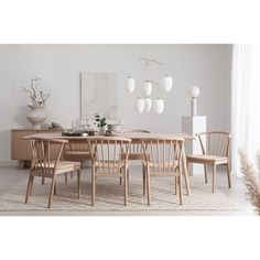 a dining room table and chairs in front of a large window with white vases