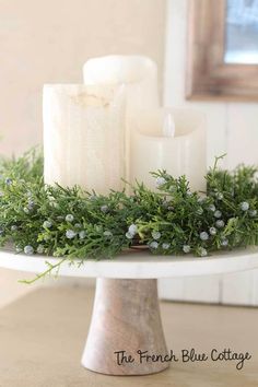 a white cake plate topped with candles and greenery