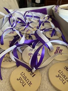 purple and white wedding favors in a box with ribbons on the table next to each other