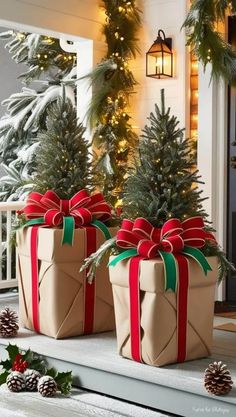 two wrapped presents sitting on top of a porch next to christmas trees and pine cones