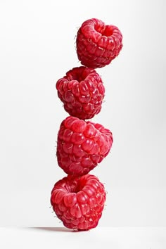 three raspberries stacked on top of each other in front of a white background