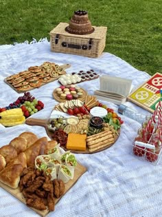 a picnic table with food and snacks on it, including breads, crackers, fruit, and sandwiches