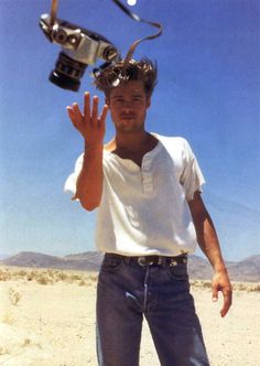 a man standing in the desert holding his hand up with a camera attached to it