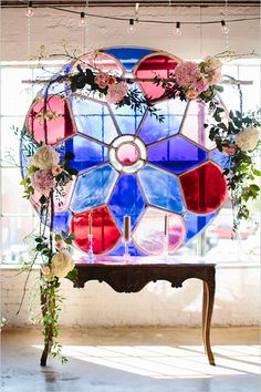 a stained glass window with flowers and greenery hanging from it's centerpiece