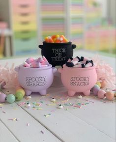 three small bowls filled with candy and candies sitting on top of a white table