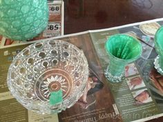 two green vases sitting on top of a table next to an open magazine and some other items