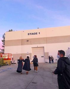 several people are standing in front of a building with a sign that says stage 1