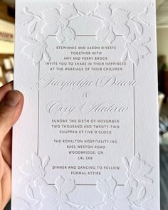 a person holding up a white wedding card