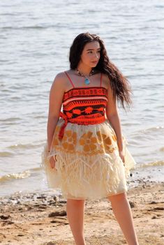 a woman standing on top of a sandy beach next to the ocean wearing a dress