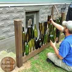 a man sitting on the ground next to a bunch of bottles that are lined up