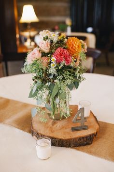 a vase filled with flowers sitting on top of a wooden table next to a candle