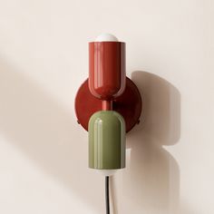 a red and green wall light on a white wall