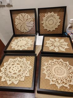 four framed lace doilies are sitting on the table