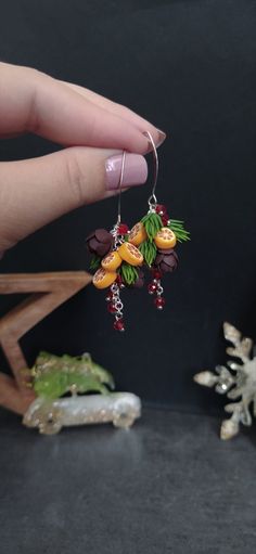 a person holding onto some kind of earrings with fruit hanging from it's hooks